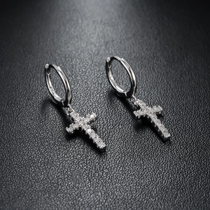 Vue macro de boucles d'oreilles croix en argent avec pavé de zircons sur cuir noir