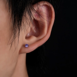 Close-up of a purple round-cut zircon ear stud with four-prong titanium setting on ear