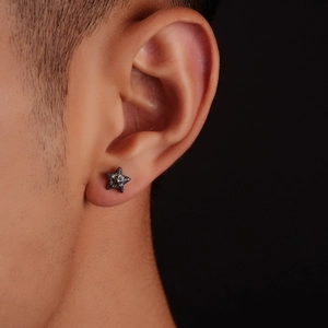 Minimalist black 3D star stud earring with crystals shown on a model's ear