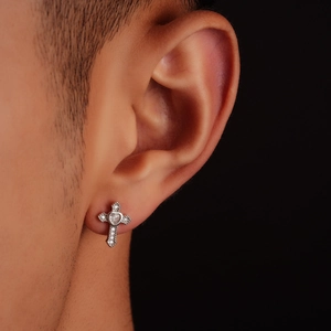 Close-up of cross stud earring with heart-cut zircon and pavé setting on ear