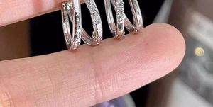 Dettaglio ravvicinato di tre piccoli orecchini in argento con pietre di zircone