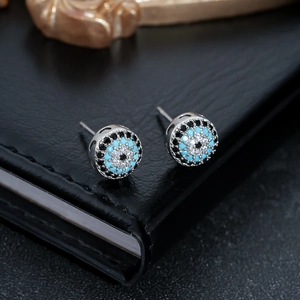 Nahaufnahme von silbernen Evil Eye Ohrsteckern mit Zirkonia auf schwarzer Lederstruktur