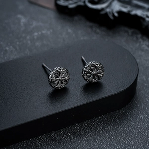 Close-up of black retro round stud earrings with embossed cross detail in gothic style