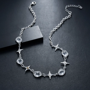 Close-up of silver chain necklace with irregular zircons and four-pointed stars detail