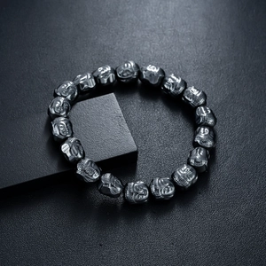 Dark gray hematite beaded bracelet with buddha head beads on textured black background