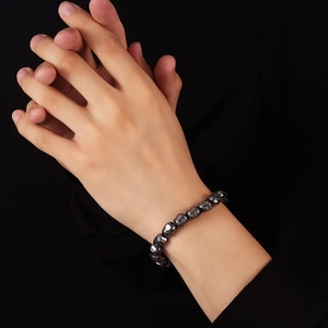 Deep grey magnetic hematite beaded bracelet featuring detailed carved Buddha head charms