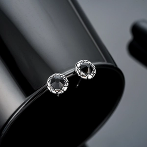 Macro shot of silver stud earring with round black zircon and diamond pattern border