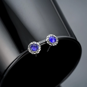 Macro detail of round blue zircon stud earring with textured silver scale pattern border