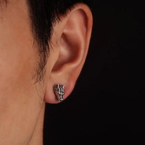 Detail shot of vintage dragon head stud earring on ear with high metallic contrast