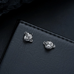 Macro shot of realistic monkey head stud earrings in vintage silver with detailed textures