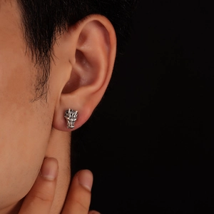 Detail of silver dragon head stud earring with vintage texture on male model ear