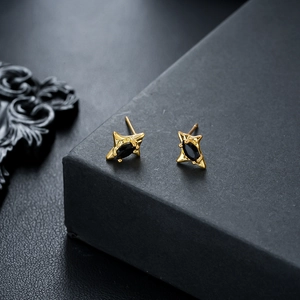 Close-up of irregular gold star earrings with marquise black zircon in a dark setting