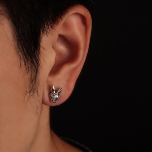 Close-up of a silver zodiac rabbit stud earring with detailed texture on model ear