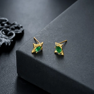 Detail of star-shaped gold earrings with marquise-cut green zircon on jewelry box