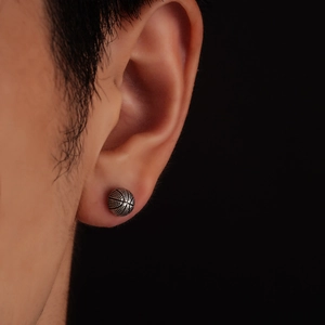 3D retro basketball stud earring with textured surface on male model earlobe