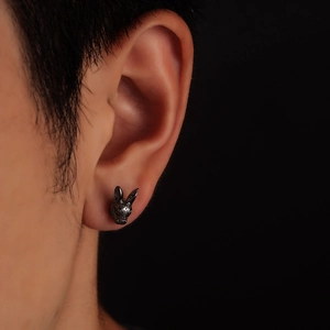 Detailed black rabbit head stud earrings with textured gunmetal finish on male model ear