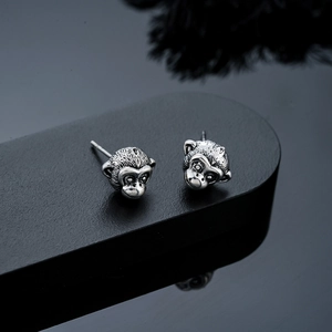 Macro detail of zodiac monkey stud earrings with antique silver finish and texture