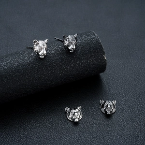 Retro silver tiger head stud earrings with detailed 3D relief on a textured stand