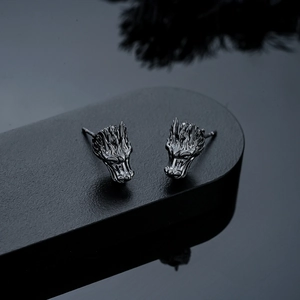 Macro detail of dark gunmetal dragon head earrings with intricate scale texture