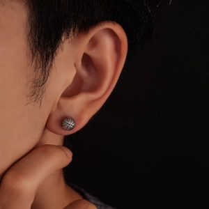 Macro shot of silver basketball earring with textured black lines for men and women