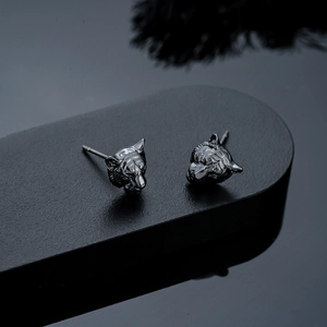 Detailed view of dark tiger head studs with intricate 3D carvings on a black stand