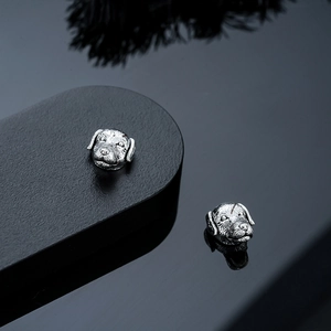 Detalle macro de pendientes magnéticos en forma de perro con acabado de plata antigua