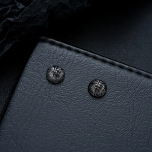 Macro shot of minimalist black basketball stud earrings with precise sphere grid texture