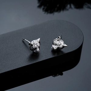 Macro shot of silver tiger head earrings with vintage textures and detailed carvings