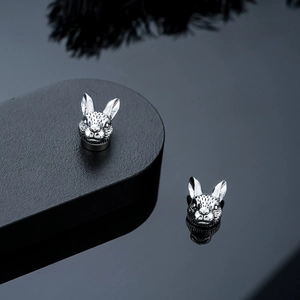 Detailed close-up of rabbit ear studs in antique silver with vintage textured patterns
