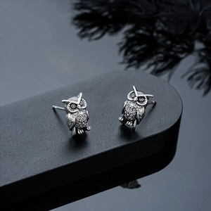 Detailed close-up of retro silver owl stud earrings with intricate embossed feather textures