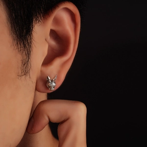 Close-up of a silver zodiac rabbit stud earring with vintage relief on a male model's ear