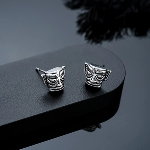 Macro view of vintage bronze Sanxingdui mask earrings with antique oxidized metal finish