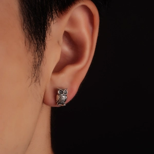 Detailed close-up of retro silver owl stud earrings with intricate embossed textures