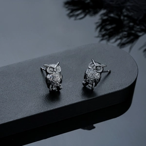 Detailed close-up of owl stud earrings with gunmetal finish and feather texture details