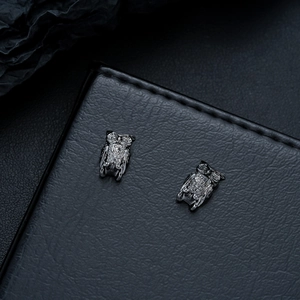 Macro shot of owl studs with detailed relief texture in vintage gunmetal finish