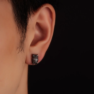 Close-up of retro black owl earring with detailed feather texture and matte finish