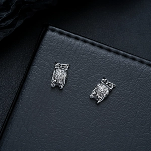 Macro shot of owl earrings in vintage silver finish with detailed feather textures