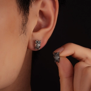 Vintage owl studs in silver finish worn on ear and held by hand for scale