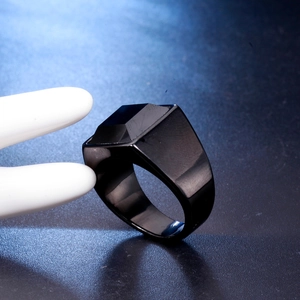 Macro close-up of a men's black geometric faceted stainless steel ring with polished edges