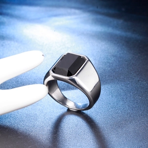 Macro view of men's wide stainless steel ring featuring a large black faceted gemstone