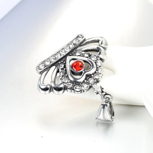 Silver crown heart pendant with red gemstone and small diamonds on a hand model