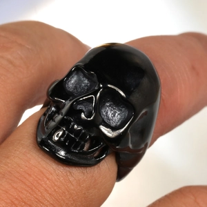 Vue macro d'une bague crâne noire style punk avec détails en argent poli sur les bords