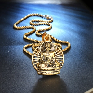 Vintage Buddha Anhänger Halskette in Gold mit Perlenkette auf strukturiertem Hintergrund
