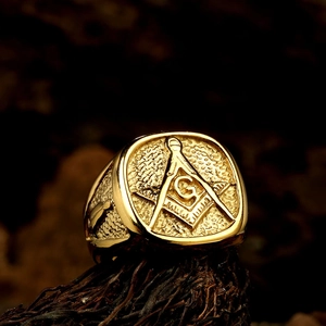 Macro shot of gold Masonic ring with Square and Compass symbol on a wooden base