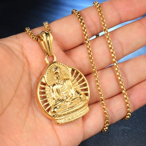 Makroaufnahme eines goldenen Buddha-Anhängers mit Box-Kette auf dunkelblauem Hintergrund