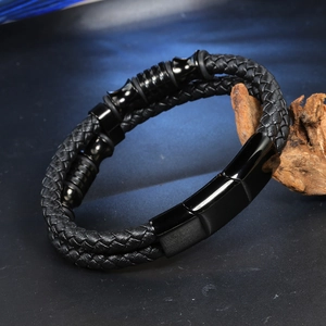Men's double-layered black woven leather bracelet with magnetic metal clasp on dark stone