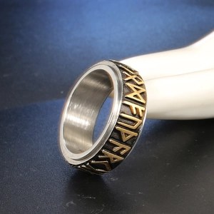 Macro shot of rotatable stainless steel ring with golden Runic symbols on black outer band