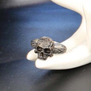 Retro punk skull ring in blackened stainless steel with a textured rock finish on a hand model