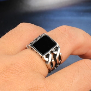 Macro shot of men's silver stainless steel ring with black gemstone and chain texture