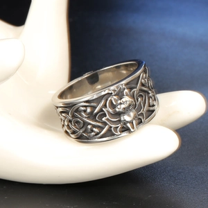 Macro shot of vintage silver skull ring with ornate floral engraving on white hand stand